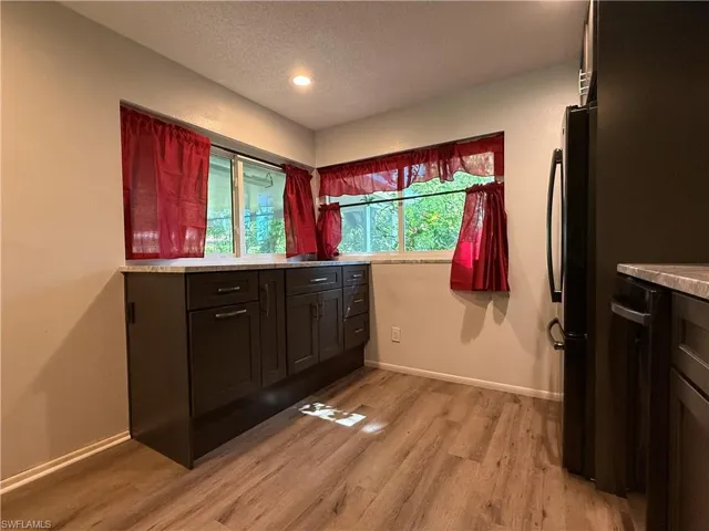 Kitchen featuring dark wood-finish cabinetry, light-toned countertops, wood-finish flooring, a built-in refrigerator, and recessed lighting