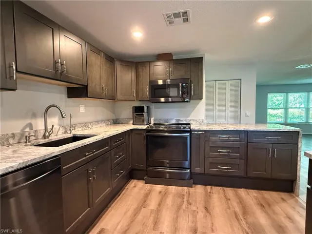 Kitchen featuring wood-finish flooring and L-shaped granite countertops