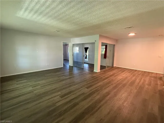 Spacious interior room featuring wood-finish flooring, light-toned walls, and recessed lighting