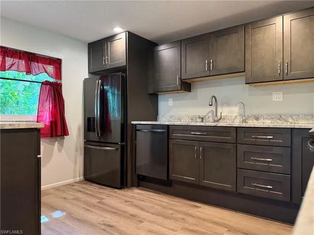 Kitchen featuring dark wood-finish cabinetry with silver hardware, light-toned countertops, and wood-finish flooring