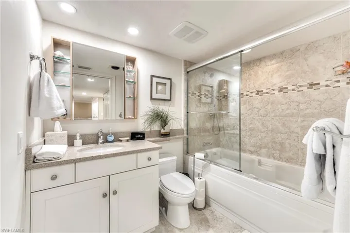 Bathroom featuring combined bath / shower with glass door, vanity, and recessed lighting