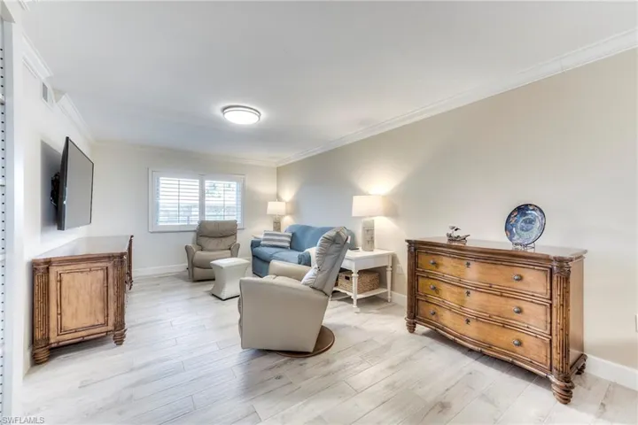 Sitting room with ornamental molding and light wood-style floors