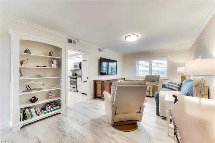 Living area with crown molding and light wood finished floors