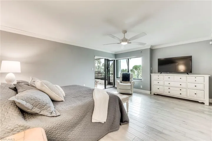 Bedroom with ornamental molding, access to outside, light wood-style floors, and a ceiling fan