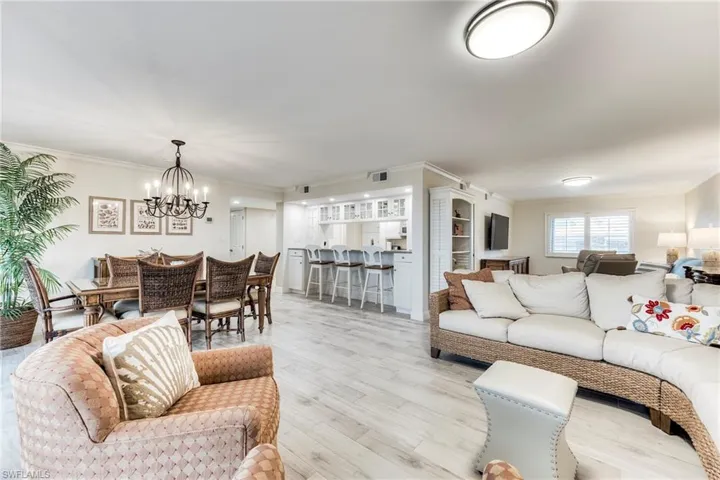 Living area with crown molding, wood finished floors, and a chandelier