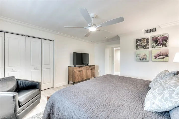 Bedroom featuring crown molding, a closet, a ceiling fan, and light wood-style flooring