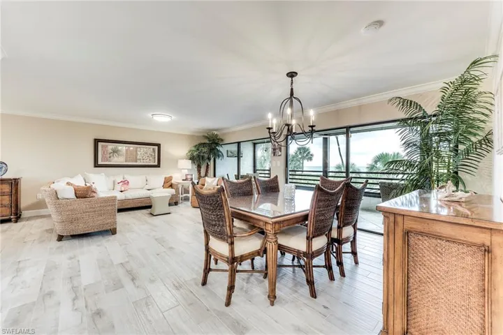 Dining room with ornamental molding, light wood finished floors, and a chandelier