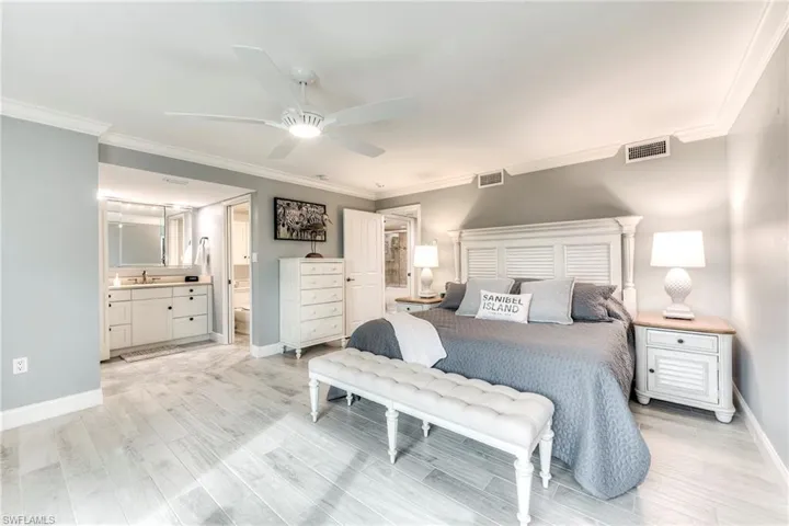 Bedroom featuring crown molding, light wood finished floors, ensuite bath, and a ceiling fan