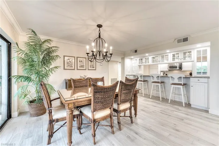 Dining space with ornamental molding, light wood-style flooring, and a chandelier