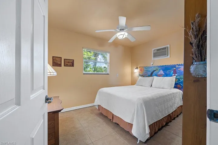 Bedroom with an AC wall unit, ceiling fan, and light tile patterned floors