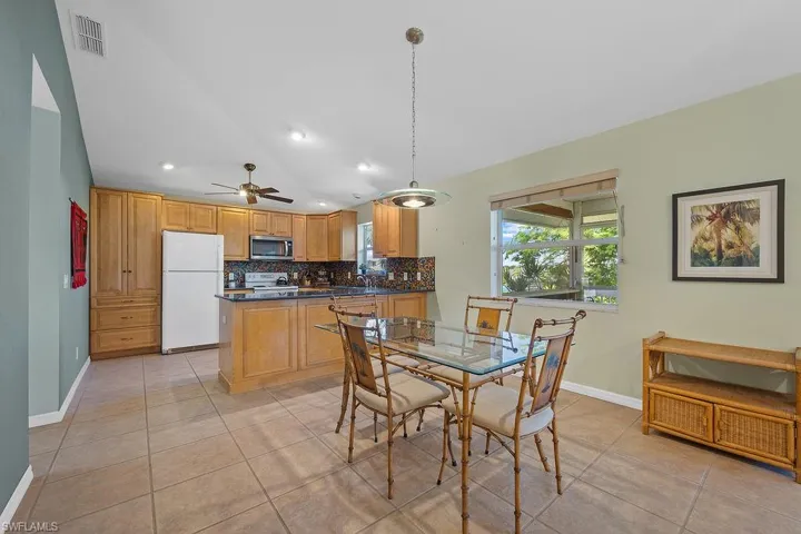 Dining room with light tile patterned floors, vaulted ceiling, and ceiling fan