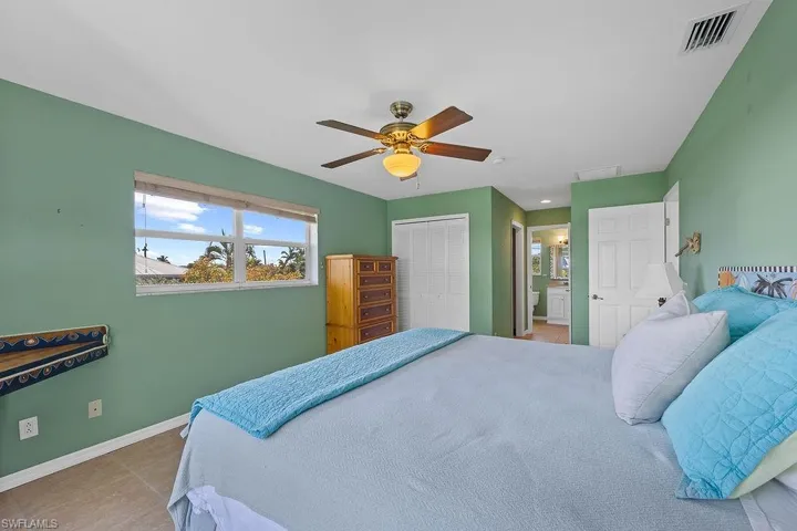 Tiled bedroom featuring ceiling fan, ensuite bathroom, and a closet