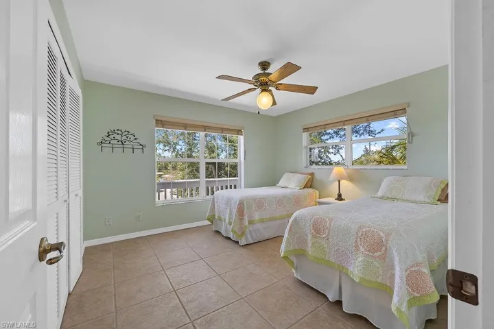 Bedroom with ceiling fan, light tile patterned flooring, and a closet