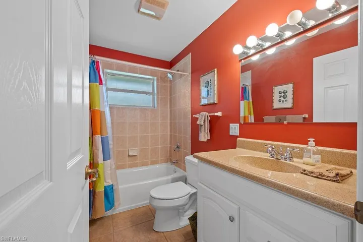 Full bathroom with shower / bath combo, vanity, tile patterned flooring, and toilet