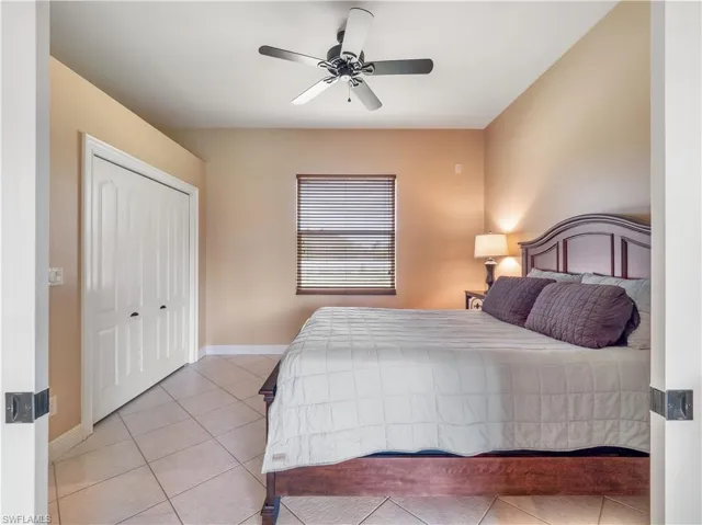 Bedroom with light tile patterned floors, a closet, and ceiling fan