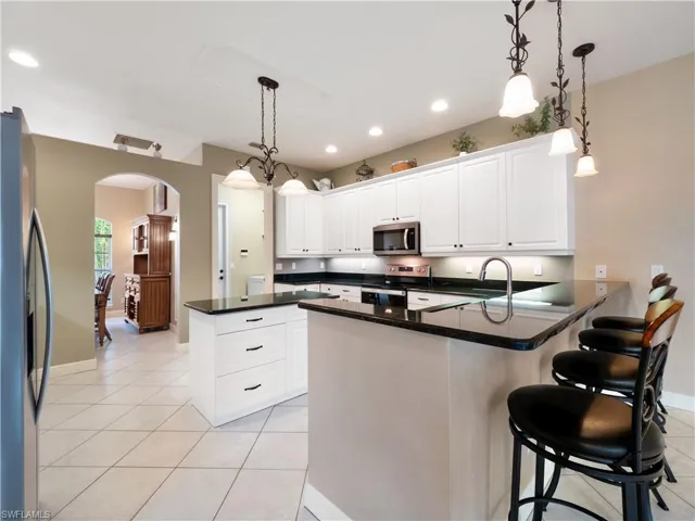 Kitchen featuring pendant lighting, white cabinetry, a kitchen bar, kitchen peninsula, and stainless steel appliances