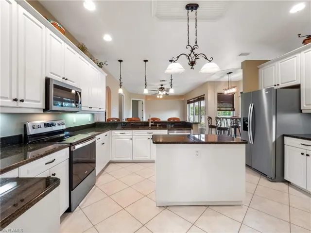 Kitchen featuring a center island, white cabinets, hanging light fixtures, appliances with stainless steel finishes, and kitchen peninsula