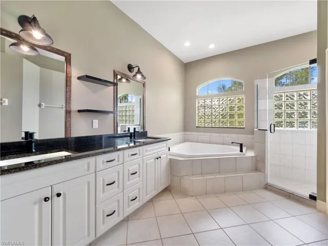 Bathroom featuring tile patterned floors, vanity, and plus walk in shower