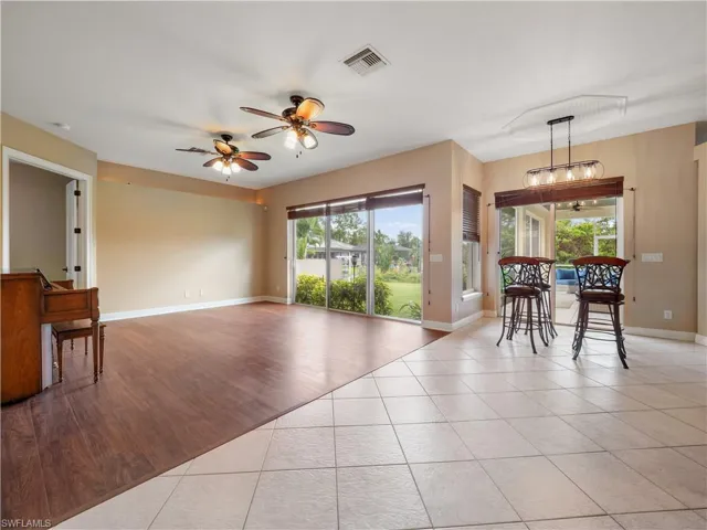Living room with light wood-type flooring, ceiling fan, and a healthy amount of sunlight