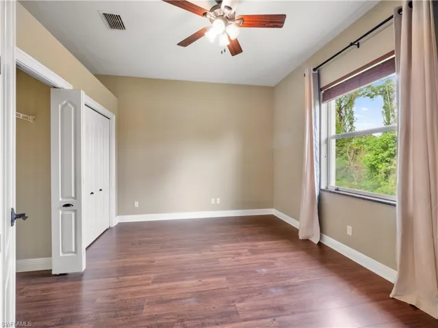 Unfurnished bedroom featuring ceiling fan and dark wood-type flooring