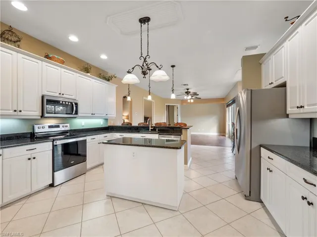 Kitchen featuring appliances with stainless steel finishes, ceiling fan, light tile patterned floors, white cabinets, and hanging light fixtures