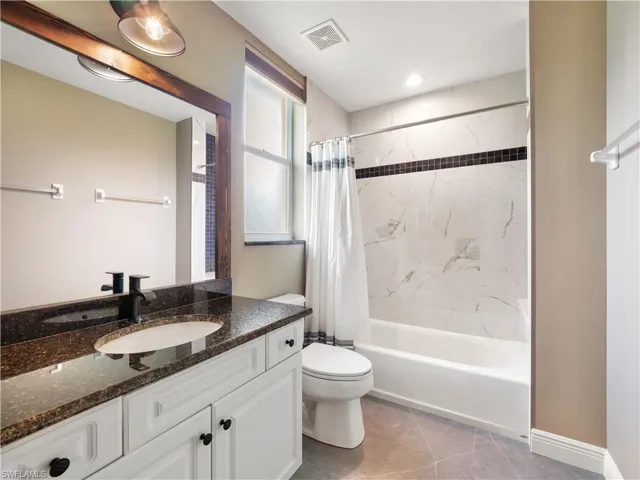 Full bathroom featuring vanity, tile patterned flooring, shower / bathtub combination with curtain, and toilet