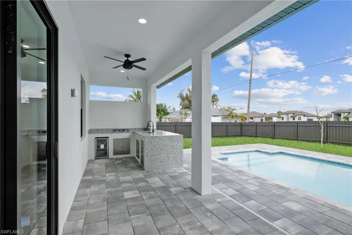 View of pool featuring ceiling fan, sink, a patio area, and exterior kitchen