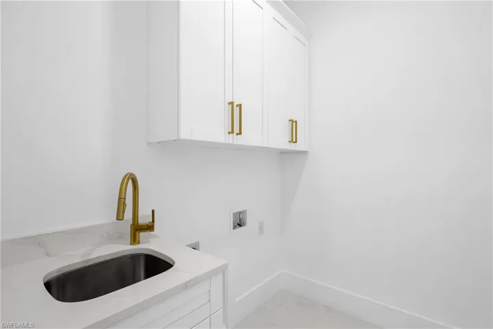 Washroom featuring sink, light tile patterned flooring, cabinets, and hookup for a washing machine