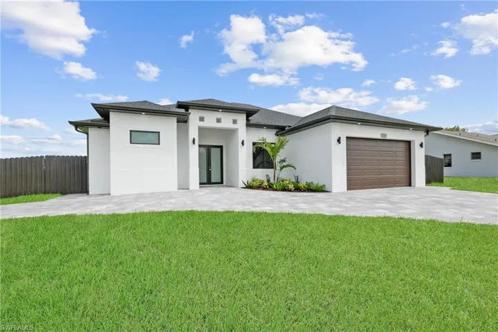 View of front of property featuring a garage and a front yard