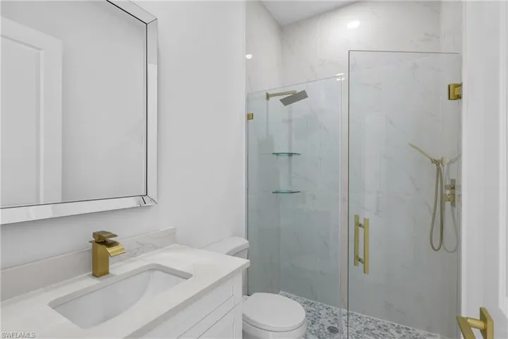 Bathroom featuring a shower with shower door, toilet, and vanity