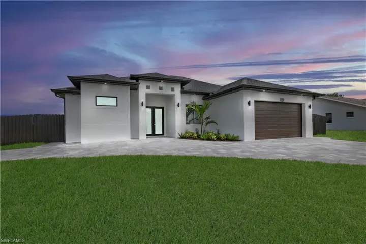 View of front of property featuring a lawn and a garage