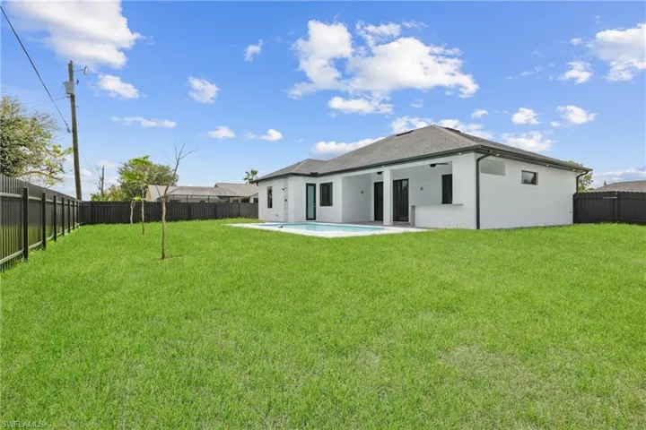 Rear view of property with a patio area, a fenced in pool, and a lawn