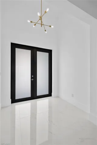 Tiled spare room with french doors and a chandelier
