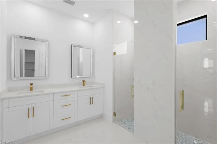 Bathroom with dual vanity, tile patterned floors, and a shower with door