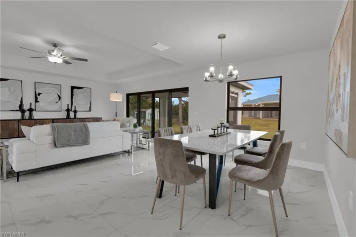 Open-concept living and dining area with large format tile flooring, a modern chandelier, and sliding glass doors