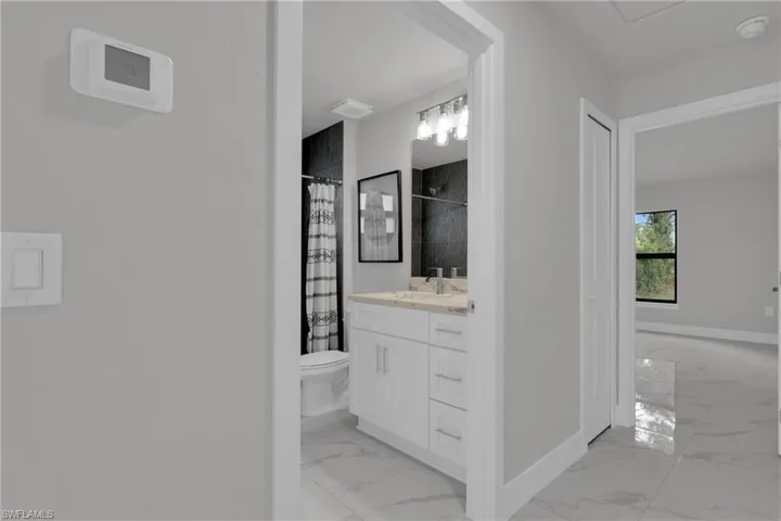 Bathroom vanity with a light-toned countertop, dual sinks, and a framed mirror