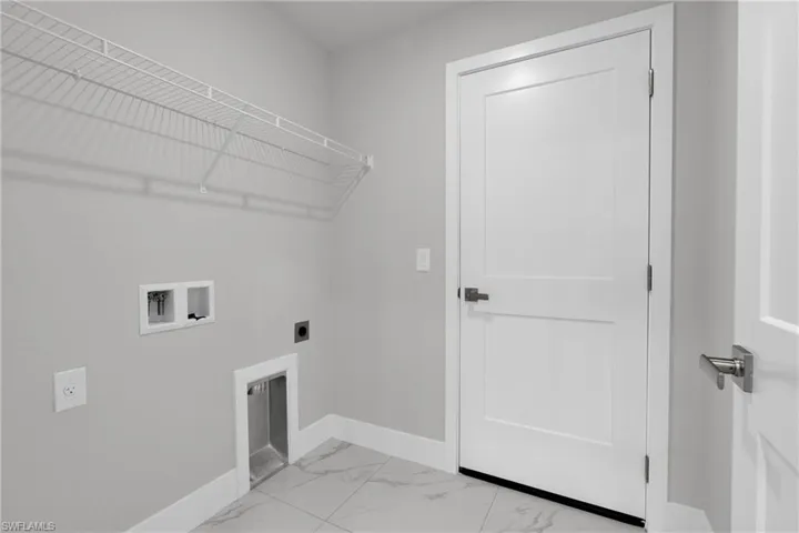 Utility space featuring a wire shelving unit, tile flooring, and a paneled interior door with dark hardware