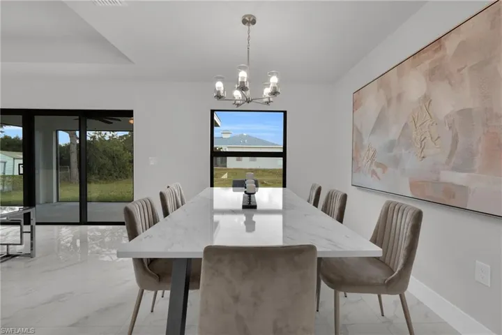 Recessed lighting with a decorative chandelier, white tile flooring, and large sliding glass doors
