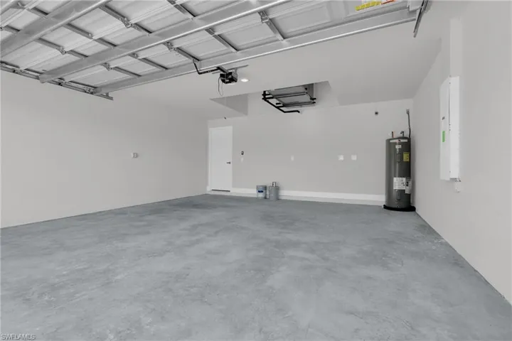 Spacious garage with concrete flooring, automatic garage door opener, and a water heater
