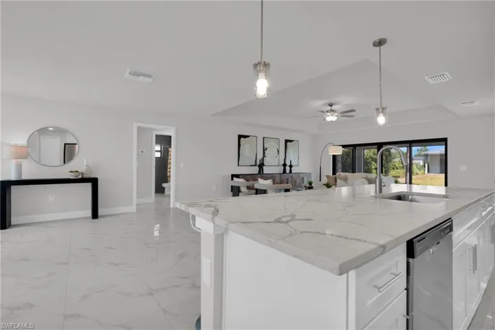 Spacious kitchen island with a single basin sink, integrated dishwasher, and pendant lighting