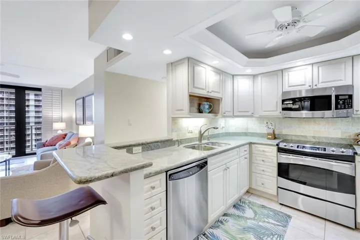 Kitchen with stainless steel appliances, light tile patterned floors, light stone countertops, ceiling fan, and recessed lighting