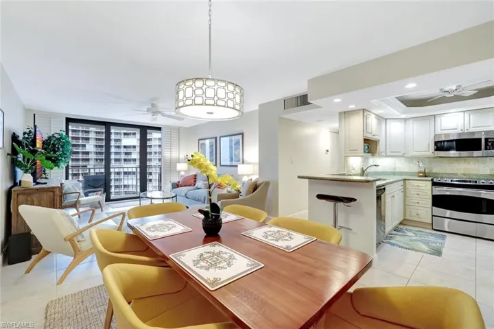 Dining space featuring ceiling fan, light tile patterned flooring, floor to ceiling windows, recessed lighting, and a raised ceiling