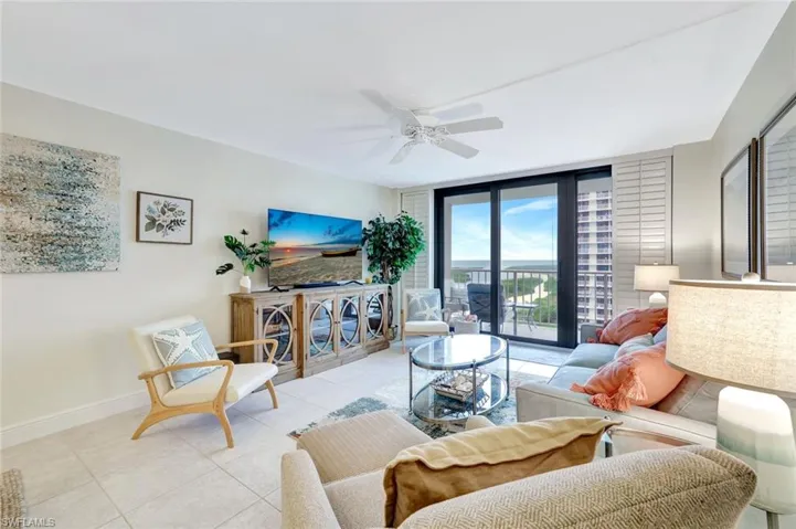 Tiled living room featuring expansive windows and a ceiling fan