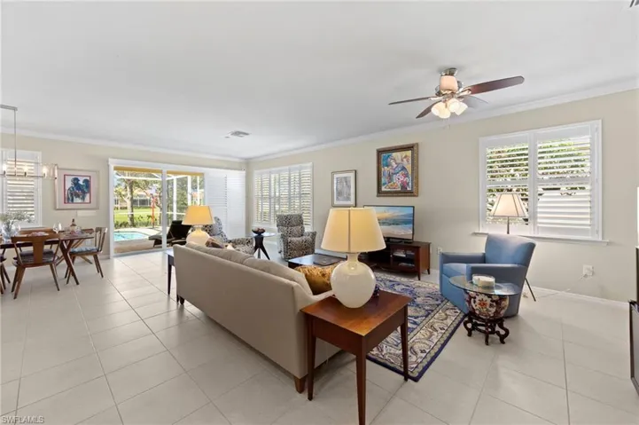 Living area featuring crown molding, light tile patterned flooring, a ceiling fan, and a chandelier