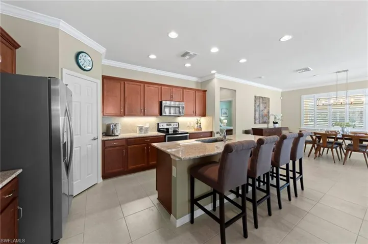 Kitchen with crown molding, stainless steel appliances, a breakfast bar area, tasteful backsplash, and a kitchen island with sink