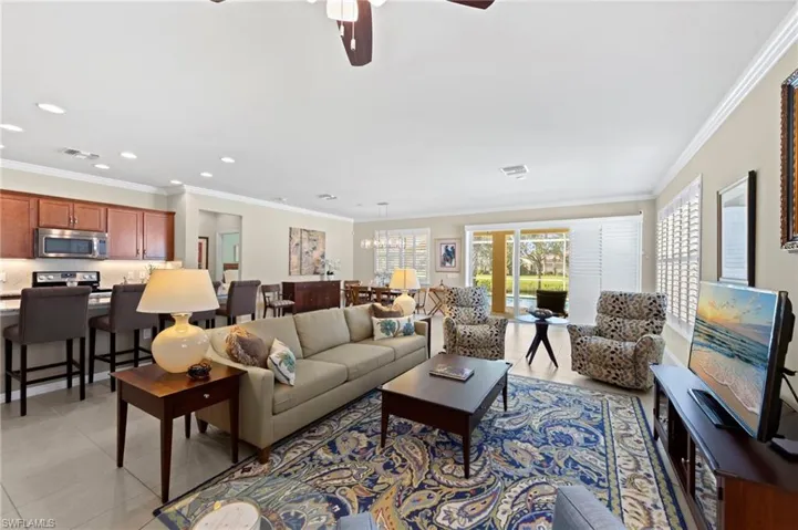 Living area with ornamental molding, a ceiling fan, light tile patterned flooring, recessed lighting, and a chandelier