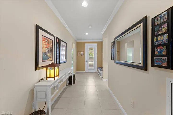 Corridor with light tile patterned flooring, crown molding, and recessed lighting