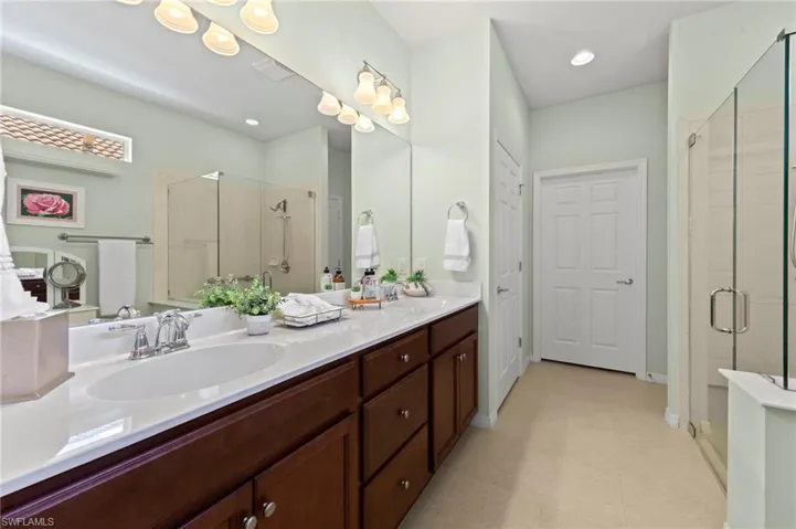Bathroom with a stall shower, double vanity, and recessed lighting