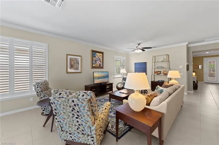 Living room with ornamental molding, light tile patterned floors, ceiling fan, and healthy amount of natural light