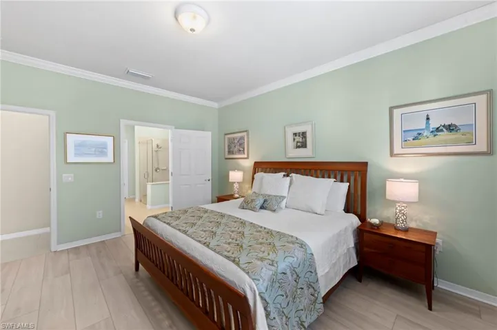 Bedroom with wood finish floors, crown molding, and ensuite bathroom